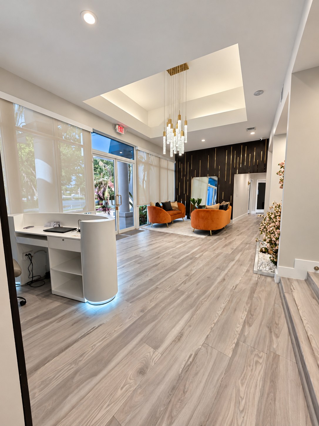 Waiting area with two curved velvet sofas facing the branded feature wall