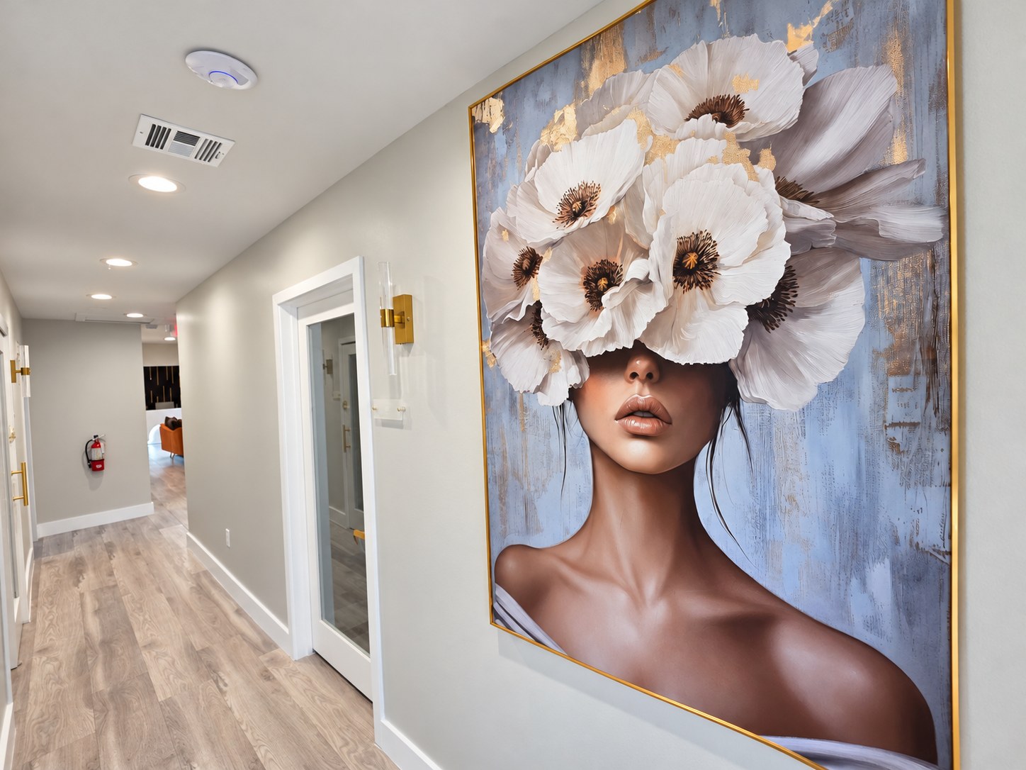 Suite corridor with brass wall sconces and a gold-framed portrait