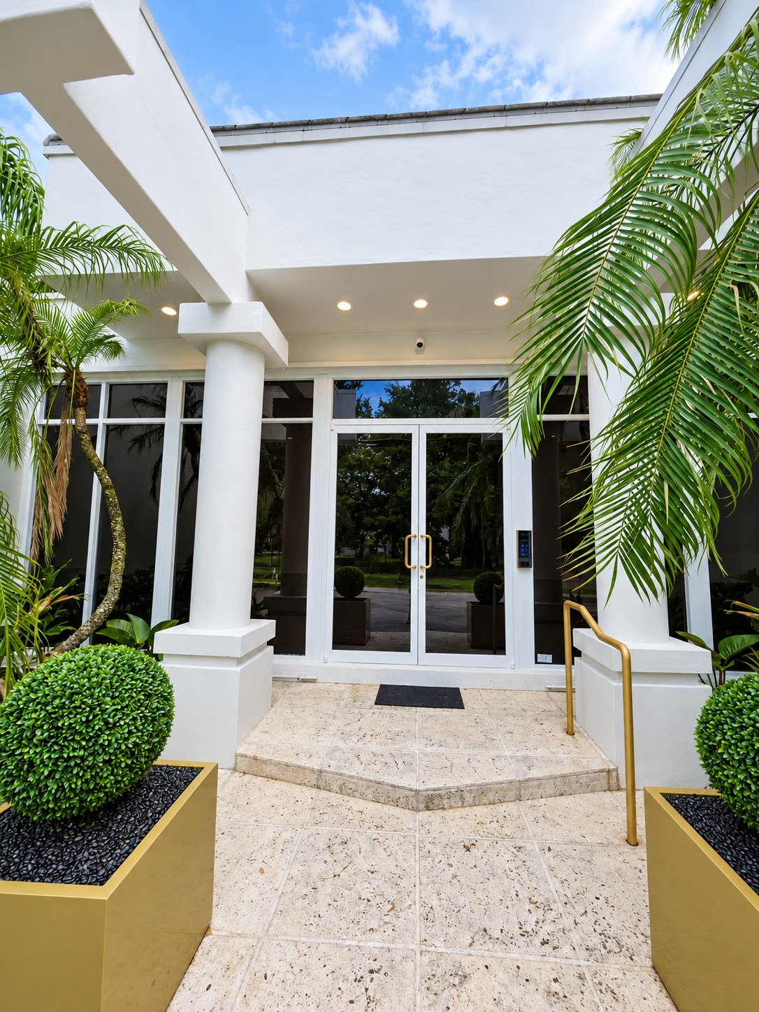 Entrance portico with stone steps, columns and glass doors in daylight