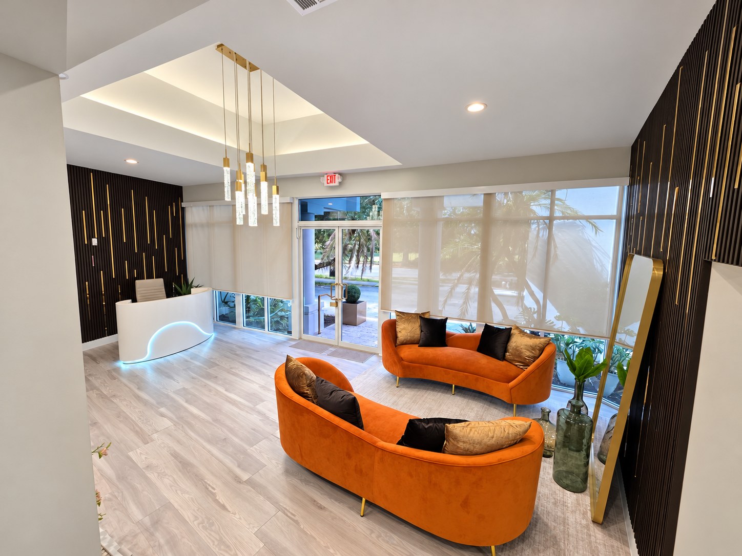 Reception lounge with curved orange velvet sofas, a white reception desk and a gold pendant chandelier