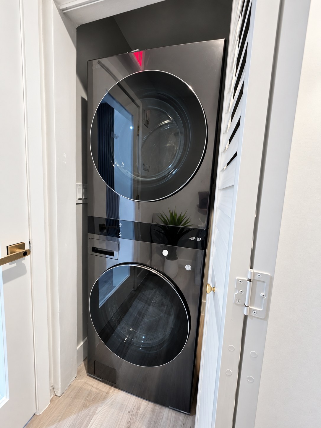 Laundry area with a stacked washer and dryer behind a louvered door